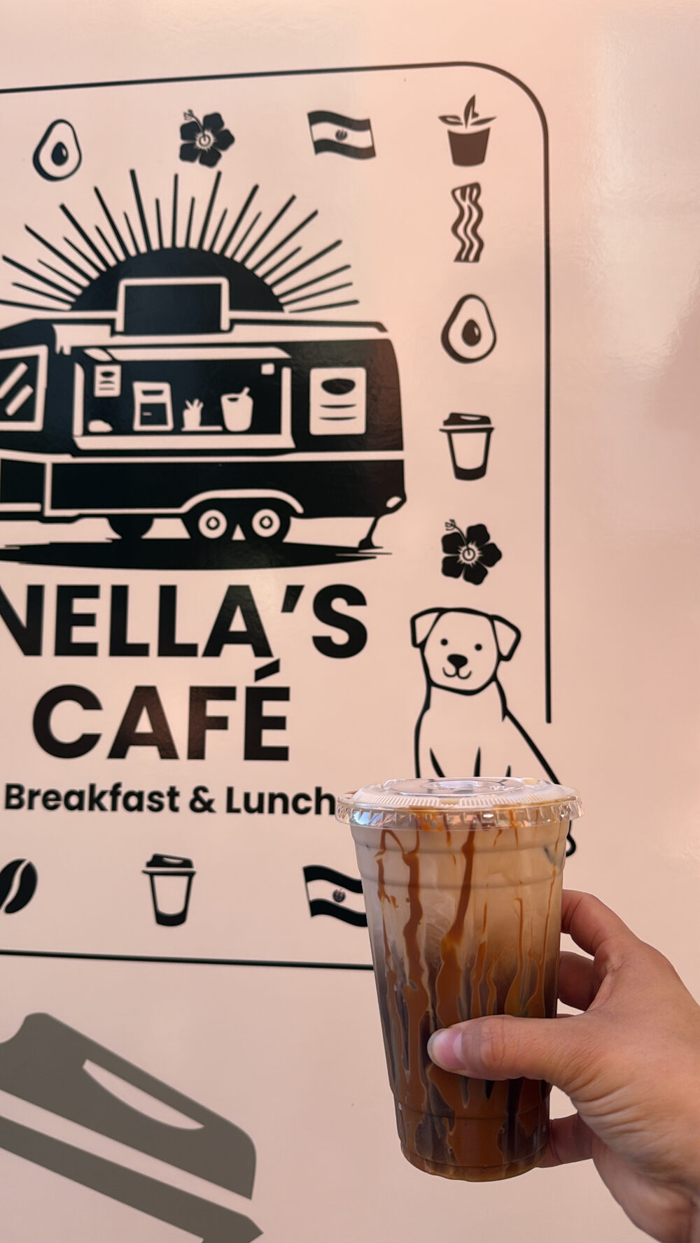 Iced coffee held up beside the Nella’s Café trailer